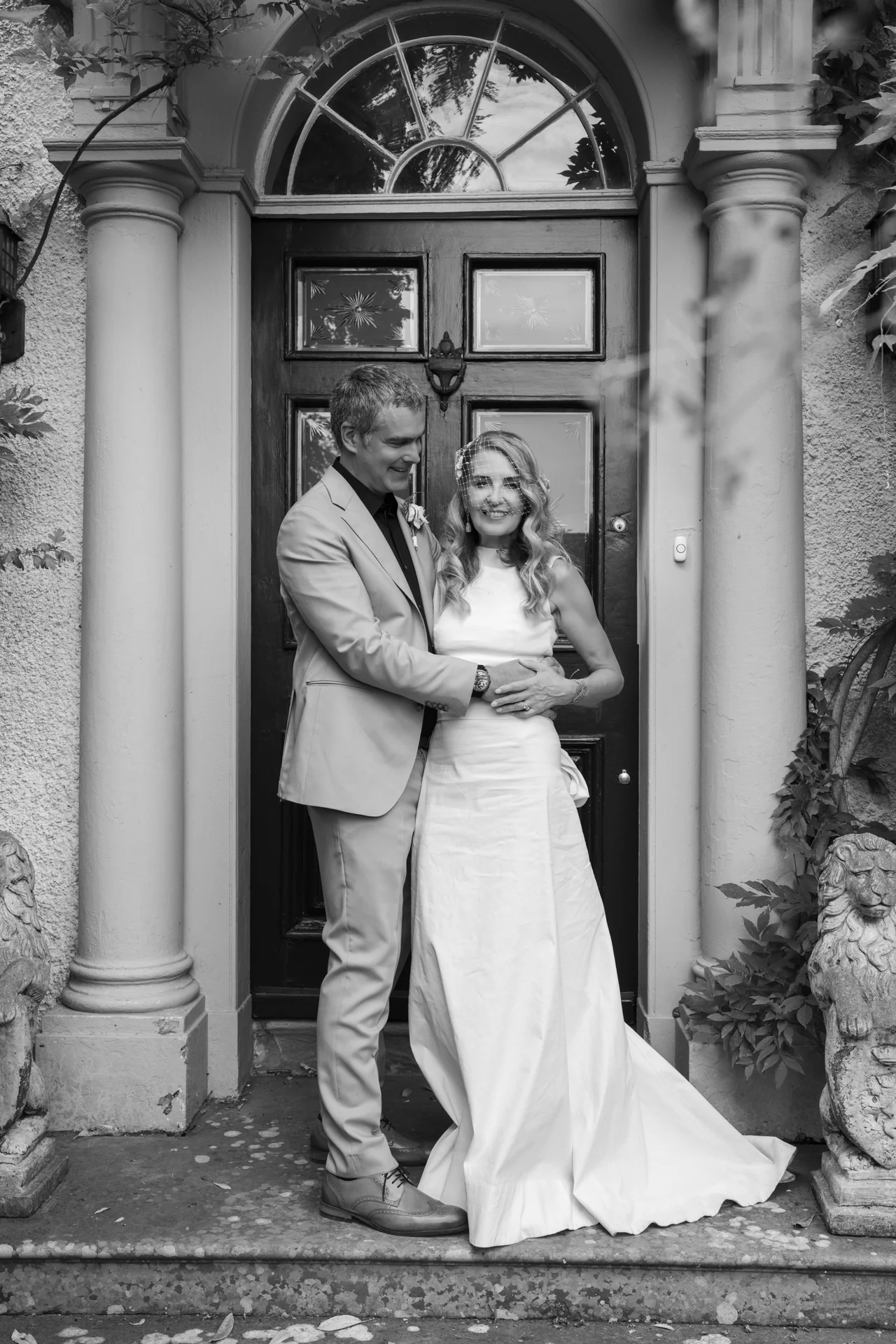 Black and white photograph of a bride and groom in a pillared doorway