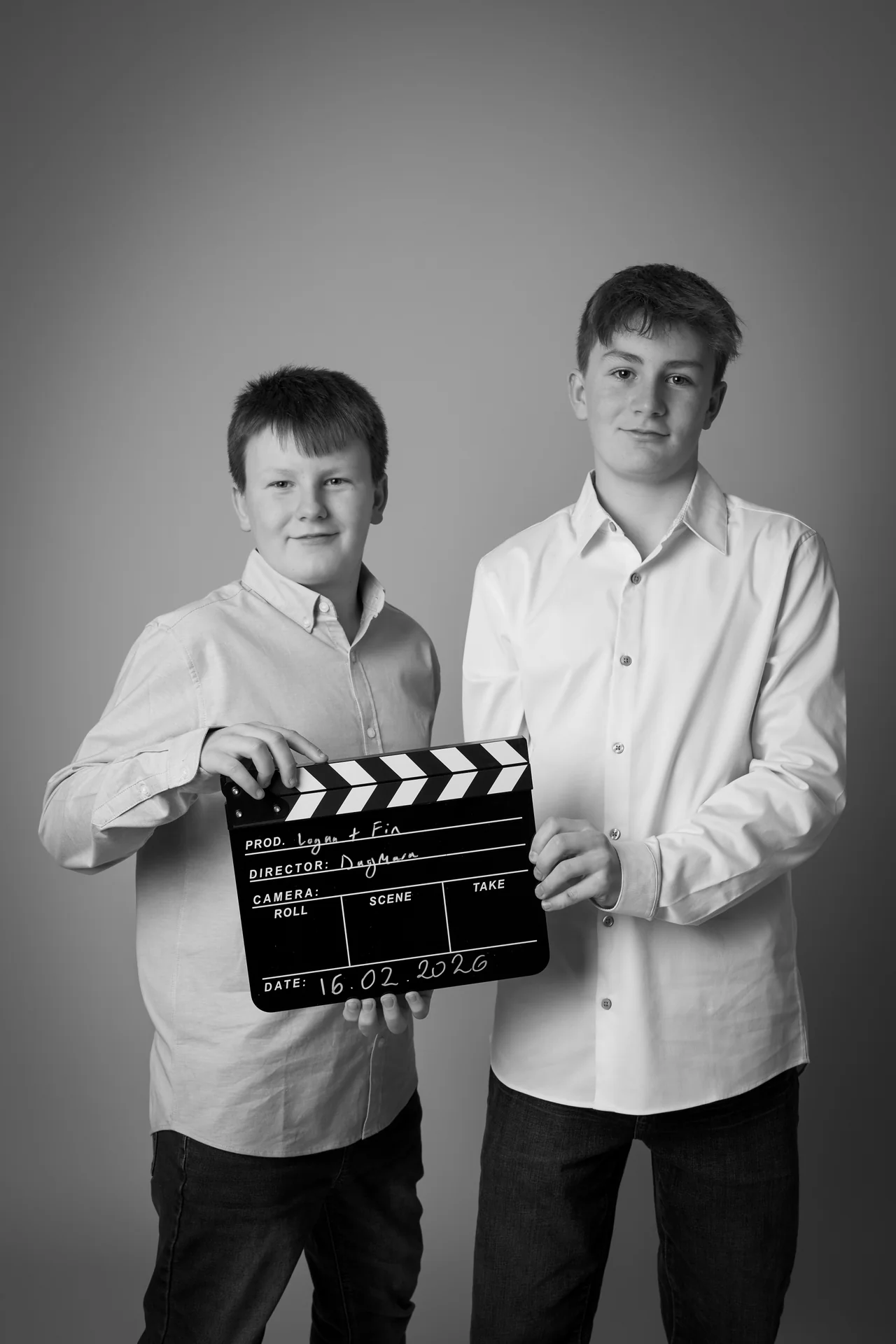 Black and white studio portrait of two brothers with a clapperboard